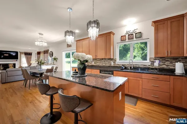 a kitchen with stainless steel appliances granite countertop wooden cabinets a dining table and chairs