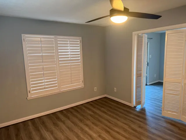 a view of an empty room with wooden floor and a window