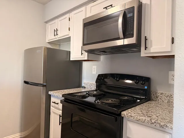 a kitchen with stainless steel appliances granite countertop white cabinets and black appliances