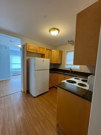 a kitchen with a sink a refrigerator and wooden floor