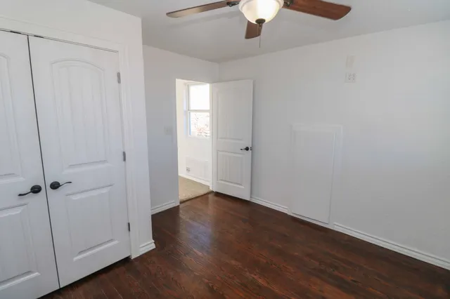 an empty room with wooden floor cabinet and windows