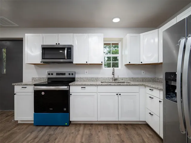 a kitchen with granite countertop a refrigerator sink and cabinets