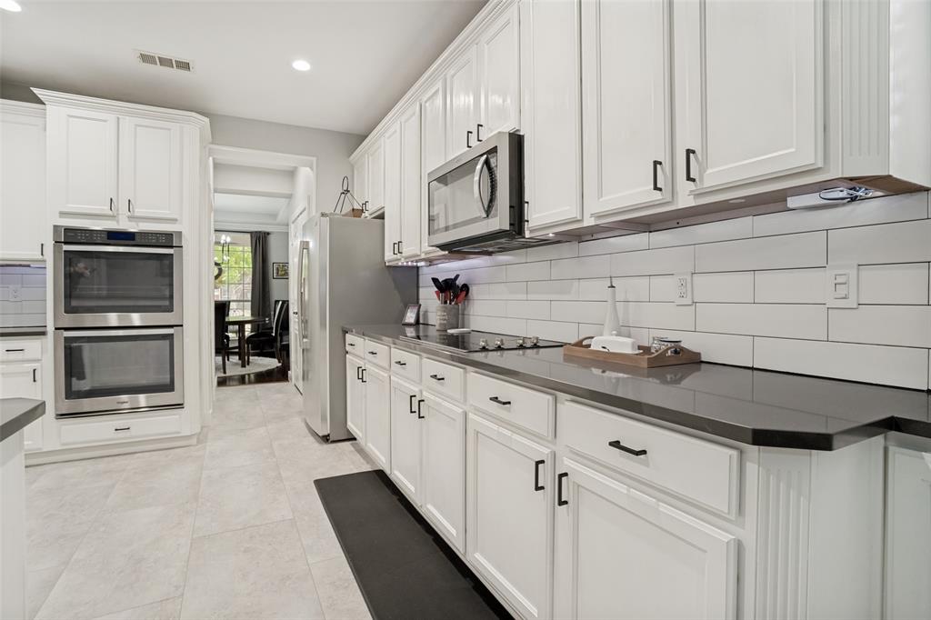 1612 Coventry Lane Allen, TX 75002 - Photo 24 of 39 Gourmet kitchen featuring white cabinetry, stainless steel double ovens, a built-in microwave, dark countertops, and a white subway tile backsplash