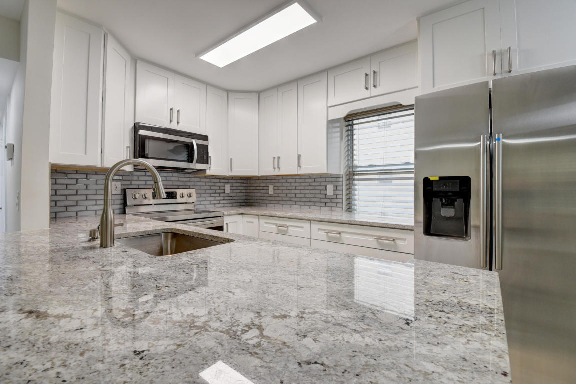 76 Flanders B Delray Beach, FL 33484 - Photo 5 of 35 a kitchen with granite countertop a refrigerator and a stove top oven