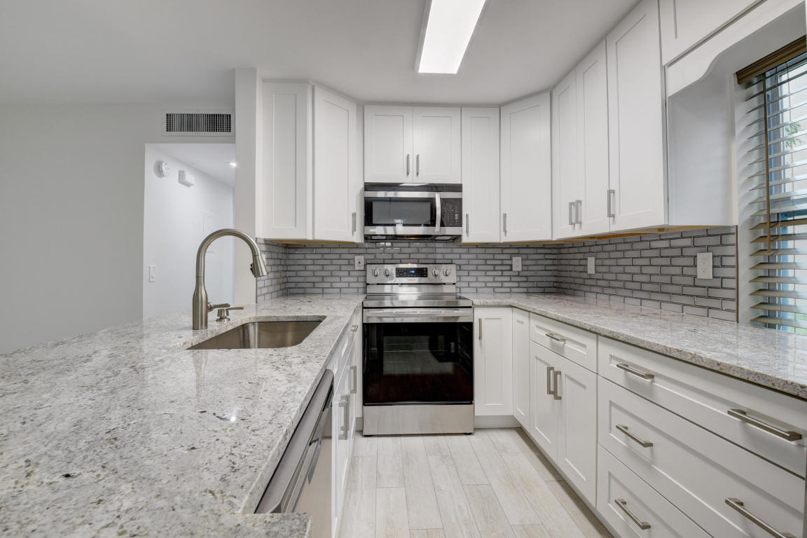 76 Flanders B Delray Beach, FL 33484 - Photo 6 of 35 a kitchen with granite countertop a stove sink and cabinets