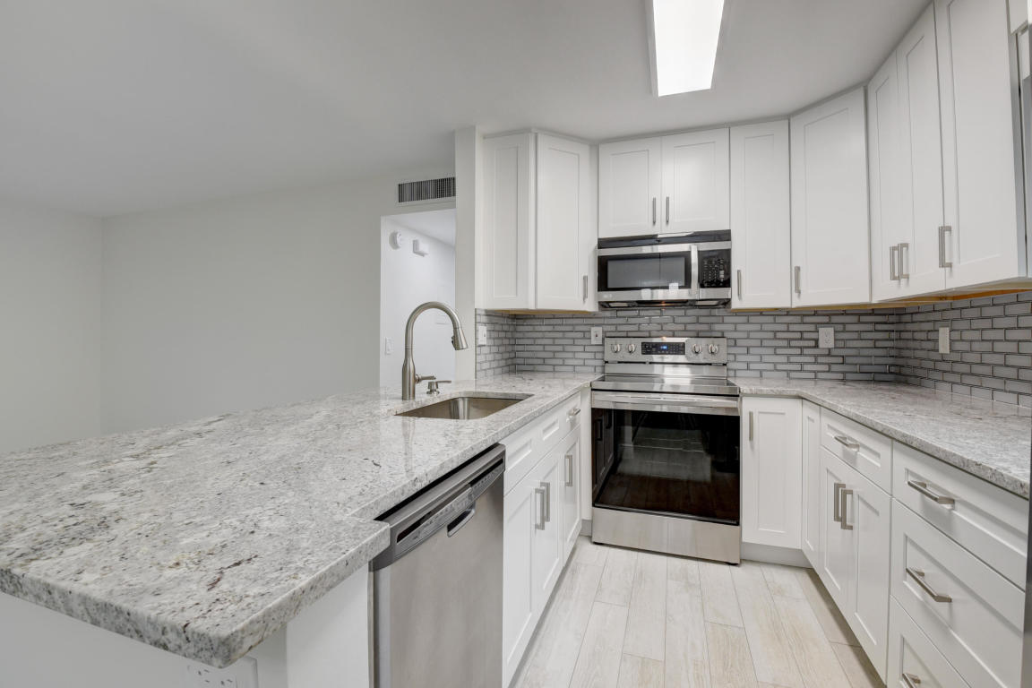 76 Flanders B Delray Beach, FL 33484 - Photo 7 of 35 a kitchen with granite countertop a stove sink and cabinets