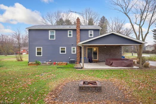4618 South Arlington Road Uniontown, OH 44685 - Photo 21 of 31 Back of property with a yard, a patio, central AC, and an outdoor fire pit