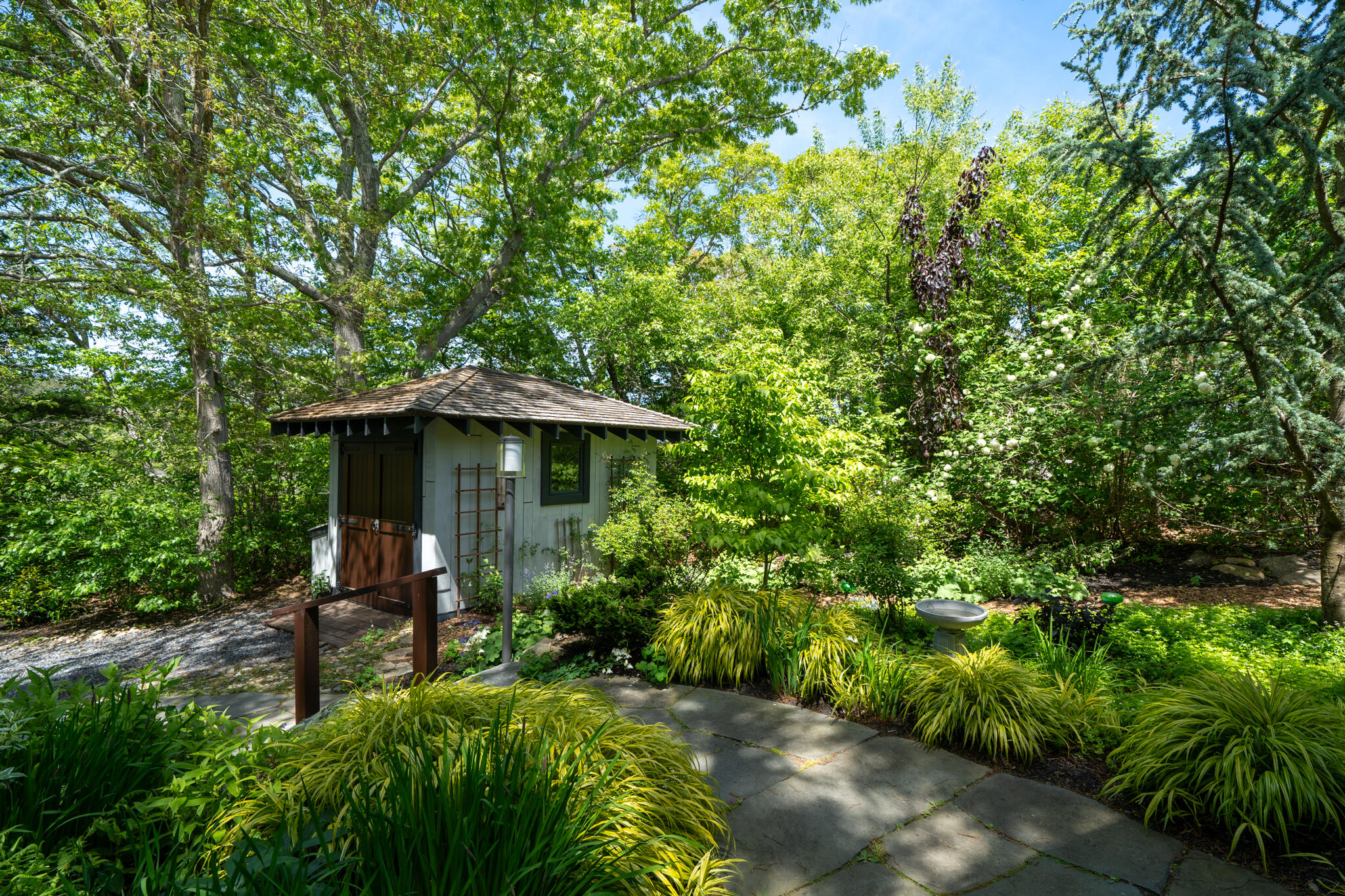 39 Sengekontacket Road Oak Bluffs, MA 02557 - Photo 6 of 32 a view of a garden with a bench under an umbrella