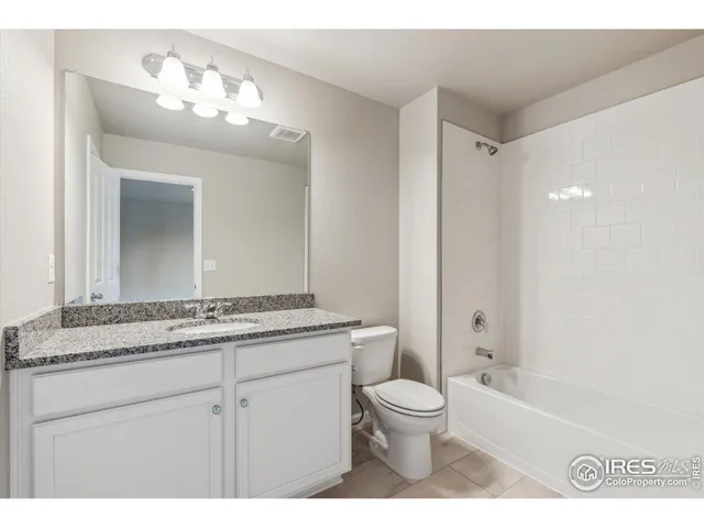 a bathroom with a granite countertop sink a toilet a mirror and bathtub