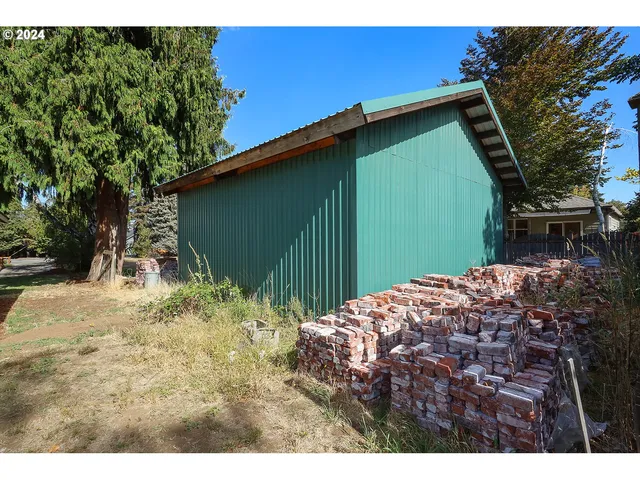 a backyard of a house with large trees and a wooden fence