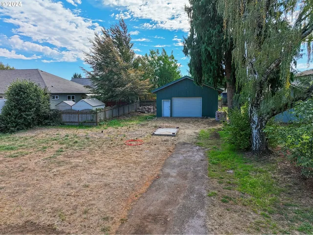 a view of a house with a yard and large tree