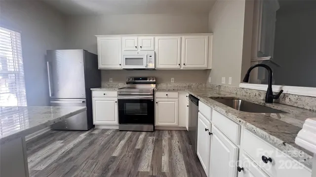 a kitchen with granite countertop a sink stainless steel appliances and cabinets
