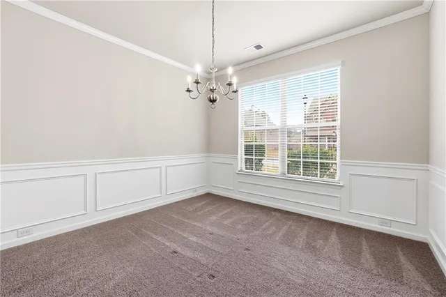 an empty room with chandelier fan and windows