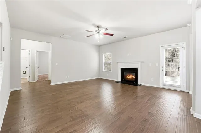 an empty room with wooden floor fireplace and windows