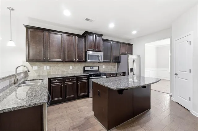 a kitchen with stainless steel appliances granite countertop a sink stove microwave and refrigerator