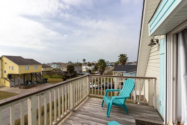 a view of a balcony with wooden chairs and floor to ceiling window