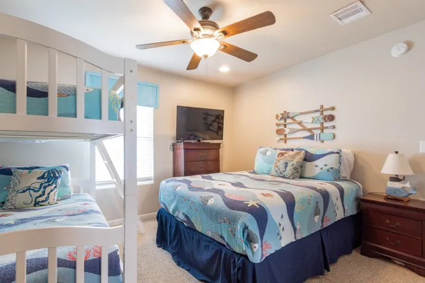 a bedroom with a bed a dresser and potted plant