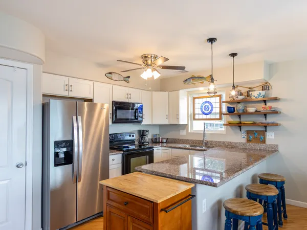 a kitchen with stainless steel appliances granite countertop a sink a stove and a refrigerator