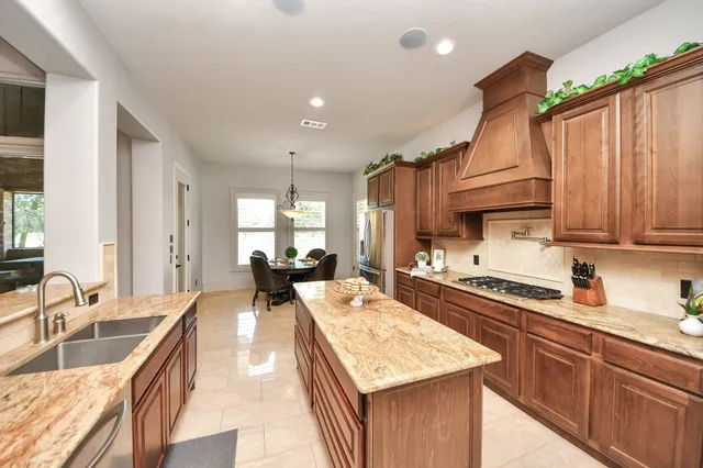 a large kitchen with kitchen island a large counter top space a sink stainless steel appliances and cabinets