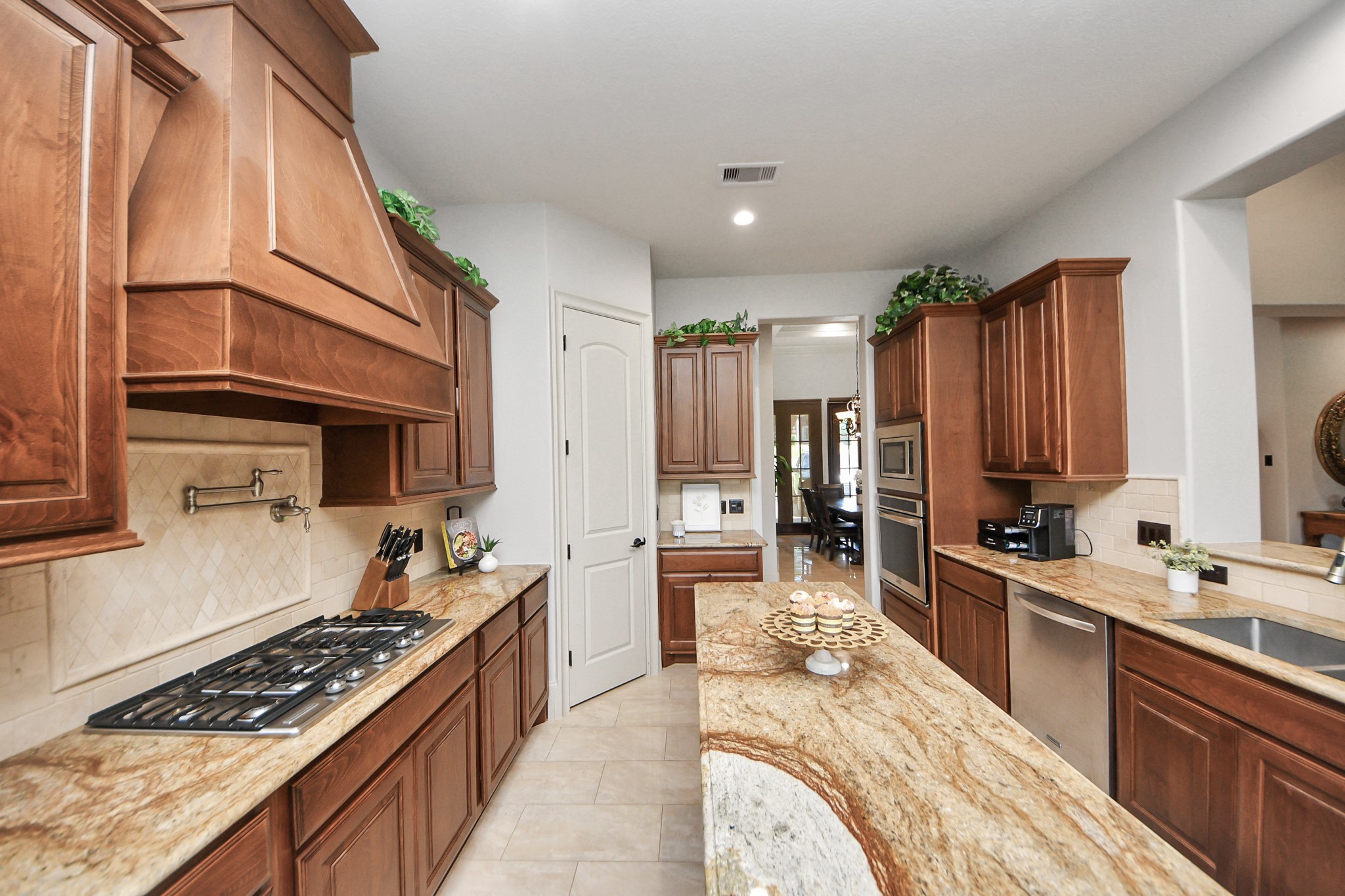 702 Fairway Oaks Conroe, TX 77302 - Photo 13 of 42 This kitchen features rich
wooden cabinetry, granite
countertops, and high-end
stainless steel appliances. It
includes a gas cooktop, double
ovens, and a spacious island,
providing ample space for
cooking and entertaining. The
neutral tile flooring and subtle
lighting enhance its modern
elegance.