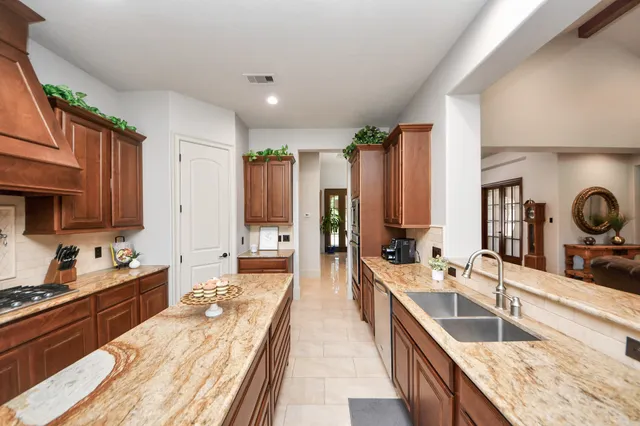 a large kitchen with kitchen island a large counter top space a sink stainless steel appliances and cabinets