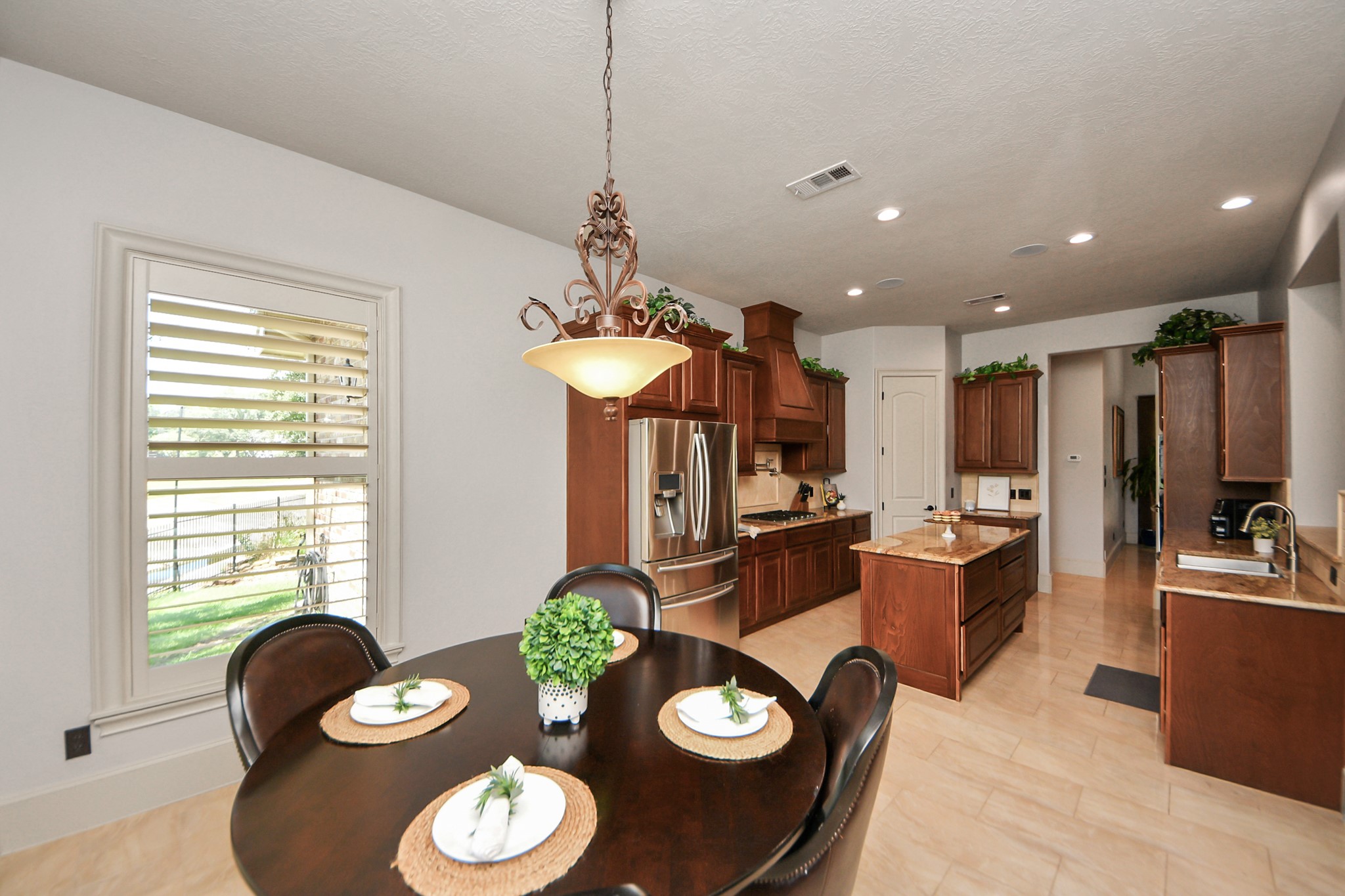 702 Fairway Oaks Conroe, TX 77302 - Photo 16 of 42 This photo showcases a
spacious, well-lit kitchen and
dining area with modern
appliances, elegant wooden
cabinetry, and a central island.
The dining area currently
features a round table with
seating and a decorative light
fixture, while a large window
offers natural light and a view
outside.