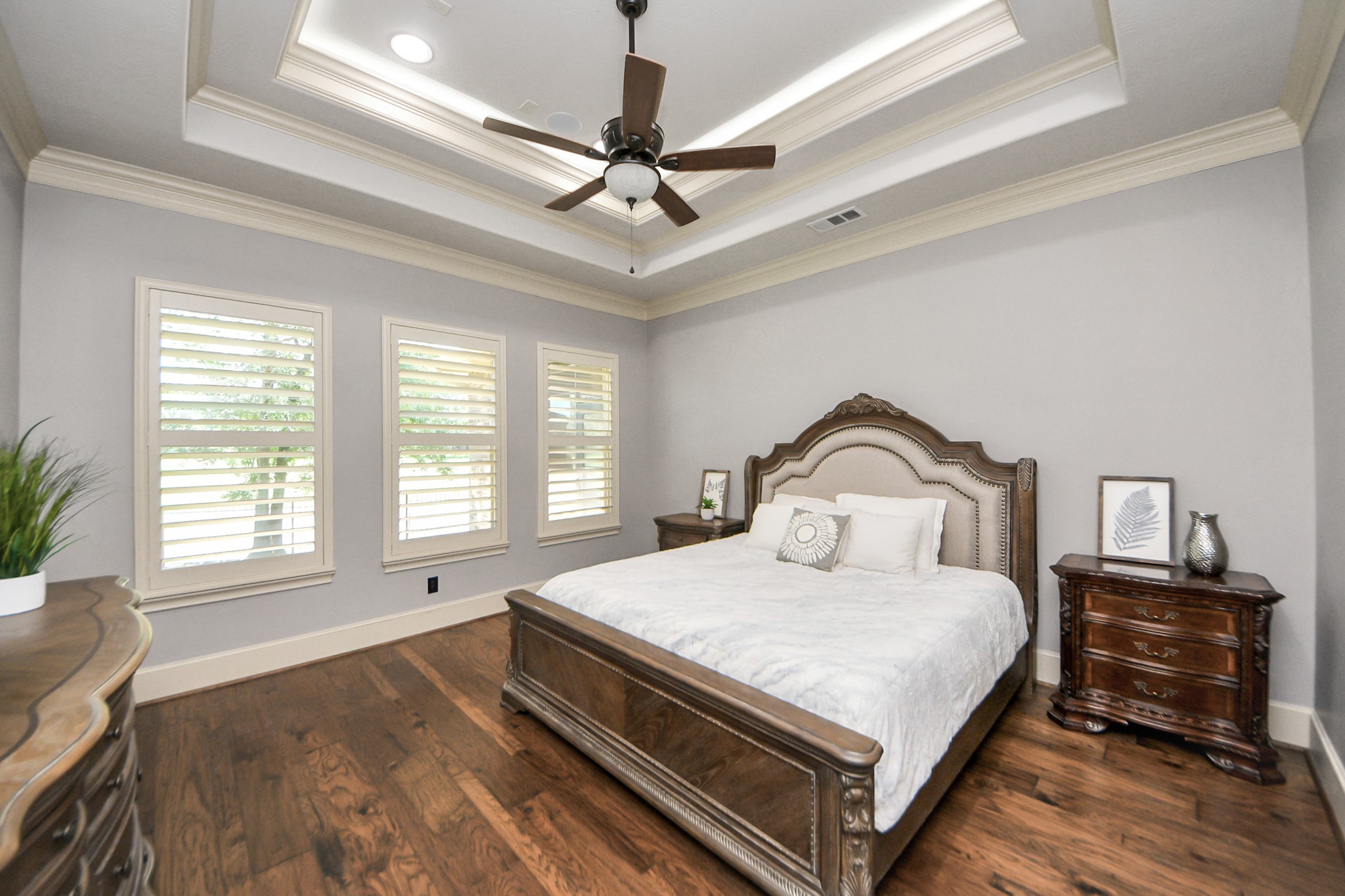 702 Fairway Oaks Conroe, TX 77302 - Photo 20 of 42 This spacious bedroom
features elegant tray ceilings, a
ceiling fan, and ample natural
light from three large windows
with shutters. It has hardwood
floors which help create a warm
and inviting atmosphere.