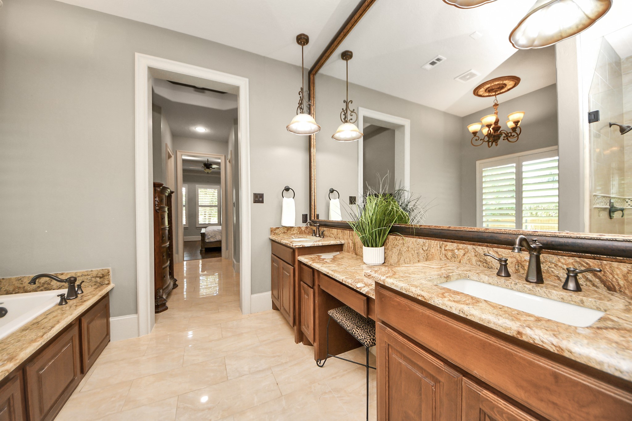 702 Fairway Oaks Conroe, TX 77302 - Photo 24 of 42 This spacious bathroom
features double sinks with
granite countertops, elegant
fixtures, a built-in bathtub, and
a large mirror. Natural light
pours in through a window with
shutters, complementing the
warm wood cabinetry and tile
flooring