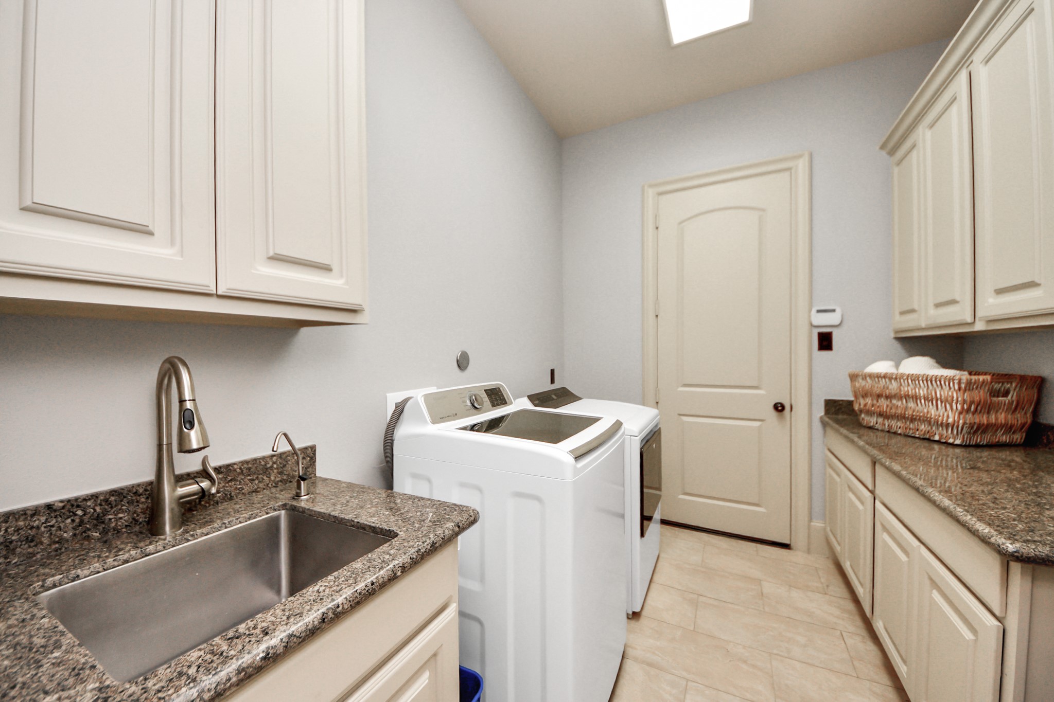 702 Fairway Oaks Conroe, TX 77302 - Photo 31 of 42 A laundry room with custom
cabinetry, granite countertops,
and tile flooring. The room even
has a sink, providing ample
storage and workspace.
