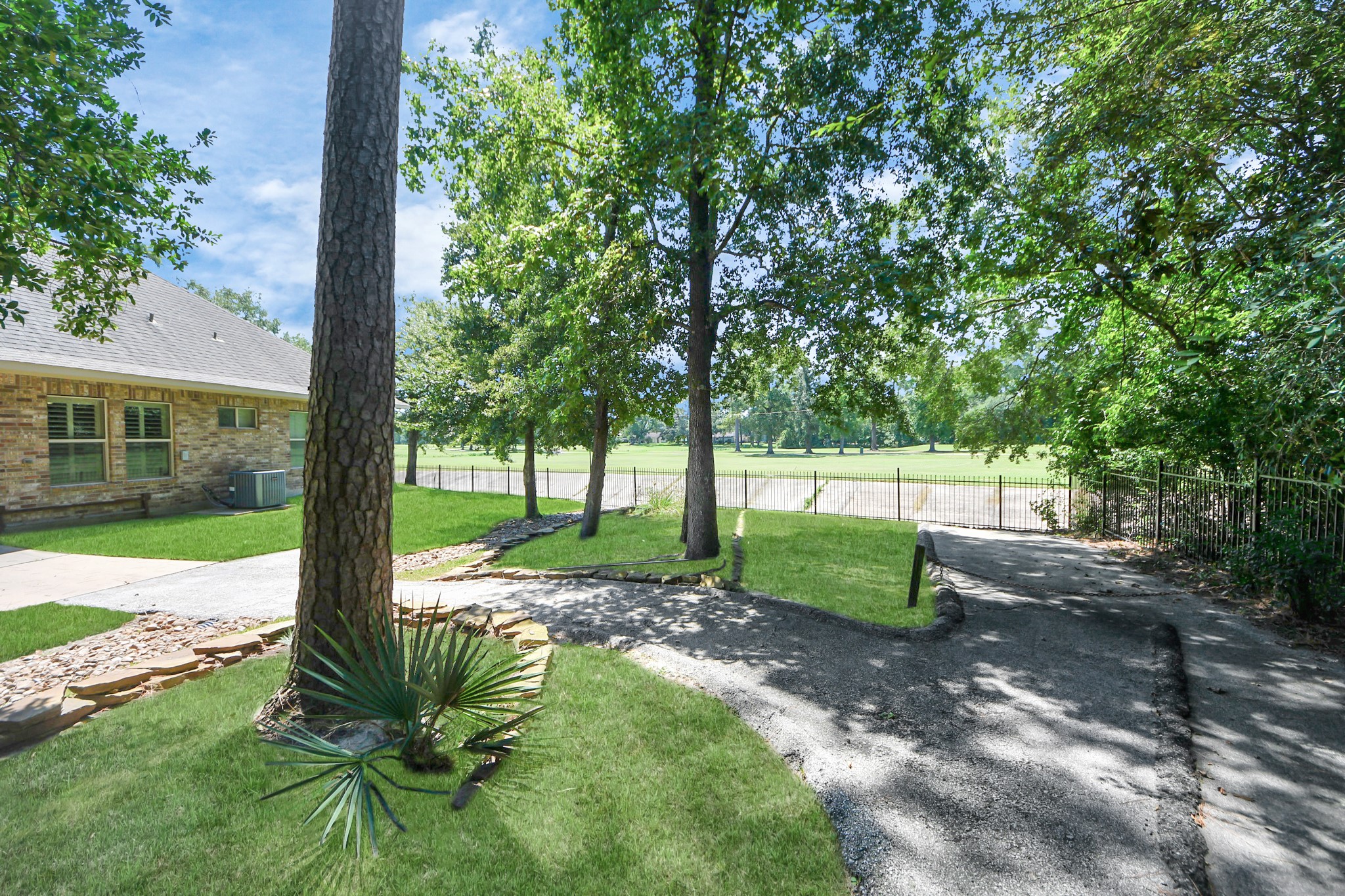 702 Fairway Oaks Conroe, TX 77302 - Photo 33 of 42 A well-maintained yard with
mature trees and a paved
driveway leading to a fenced
area. The stone exterior of the
house and manicured lawn
provide a welcoming and
serene atmosphere, ideal for
enjoying outdoor spaces.