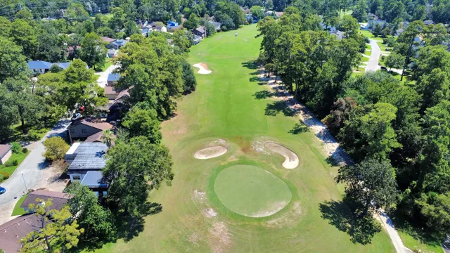 an aerial view of a house with swimming pool and trees all around