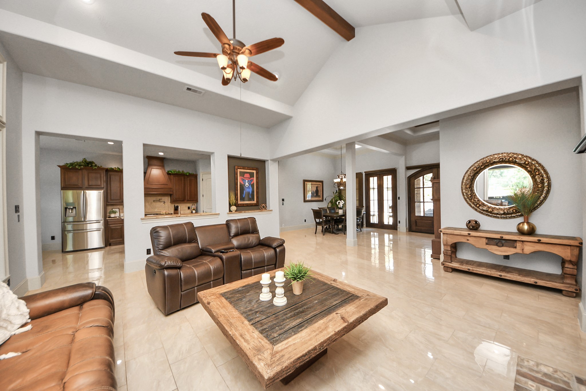 702 Fairway Oaks Conroe, TX 77302 - Photo 9 of 42 This spacious living area
features high vaulted ceilings
with exposed beams, elegant
tile flooring, and ample natural
light. It includes a cozy seating
area with leather sofas, a
wooden coffee table, and a
view into a modern kitchen with
stainless steel appliances. The
open layout extends to a dining
area, and large windows add to
the bright, airy feel