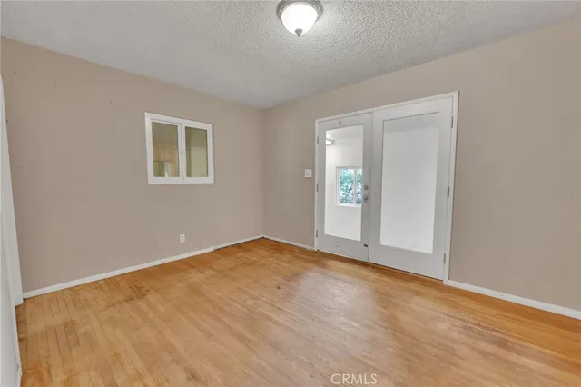a view of an empty room with window and wooden floor