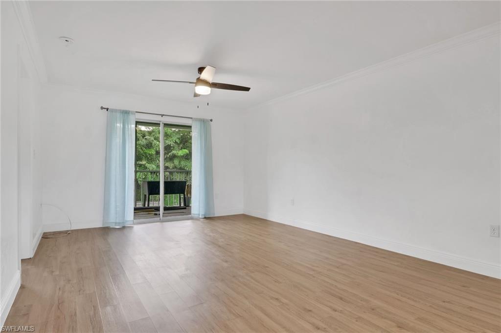146 Cypress Way East, Unit 807 Naples, FL 34110 - Photo 14 of 27 a view of an empty room with wooden floor and a window
