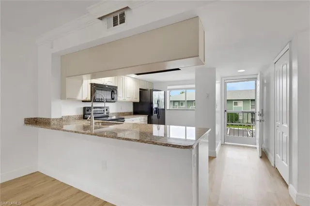 a kitchen with kitchen island granite countertop a sink cabinets and wooden floor