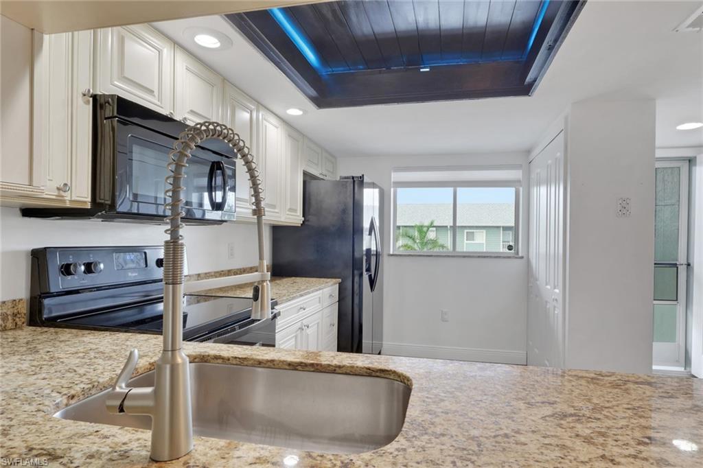 146 Cypress Way East, Unit 807 Naples, FL 34110 - Photo 7 of 27 a kitchen with stainless steel appliances granite countertop a sink and a refrigerator