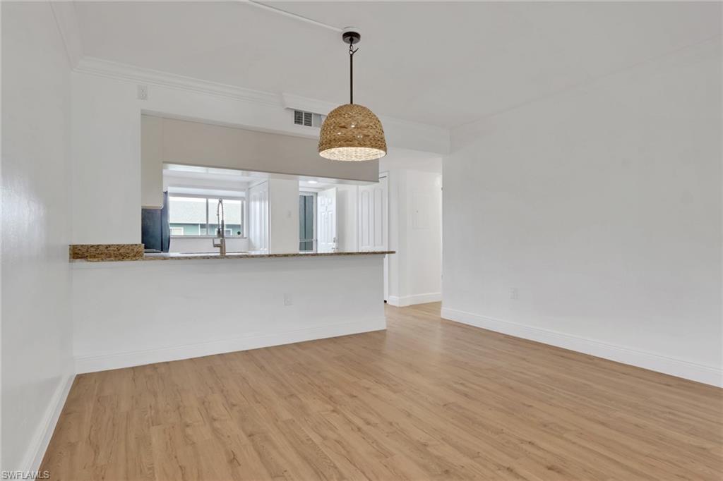146 Cypress Way East, Unit 807 Naples, FL 34110 - Photo 9 of 27 a view of a room with wooden floor and white walls