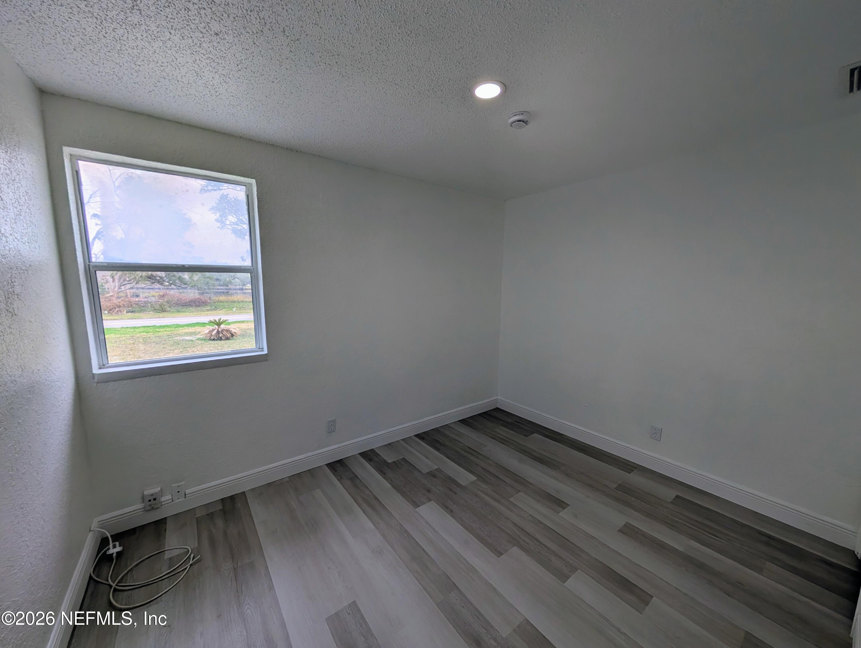 1454 Ribault Scenic Drive Jacksonville, FL 32208 - Photo 14 of 22 a view of an empty room with wooden floor and a window