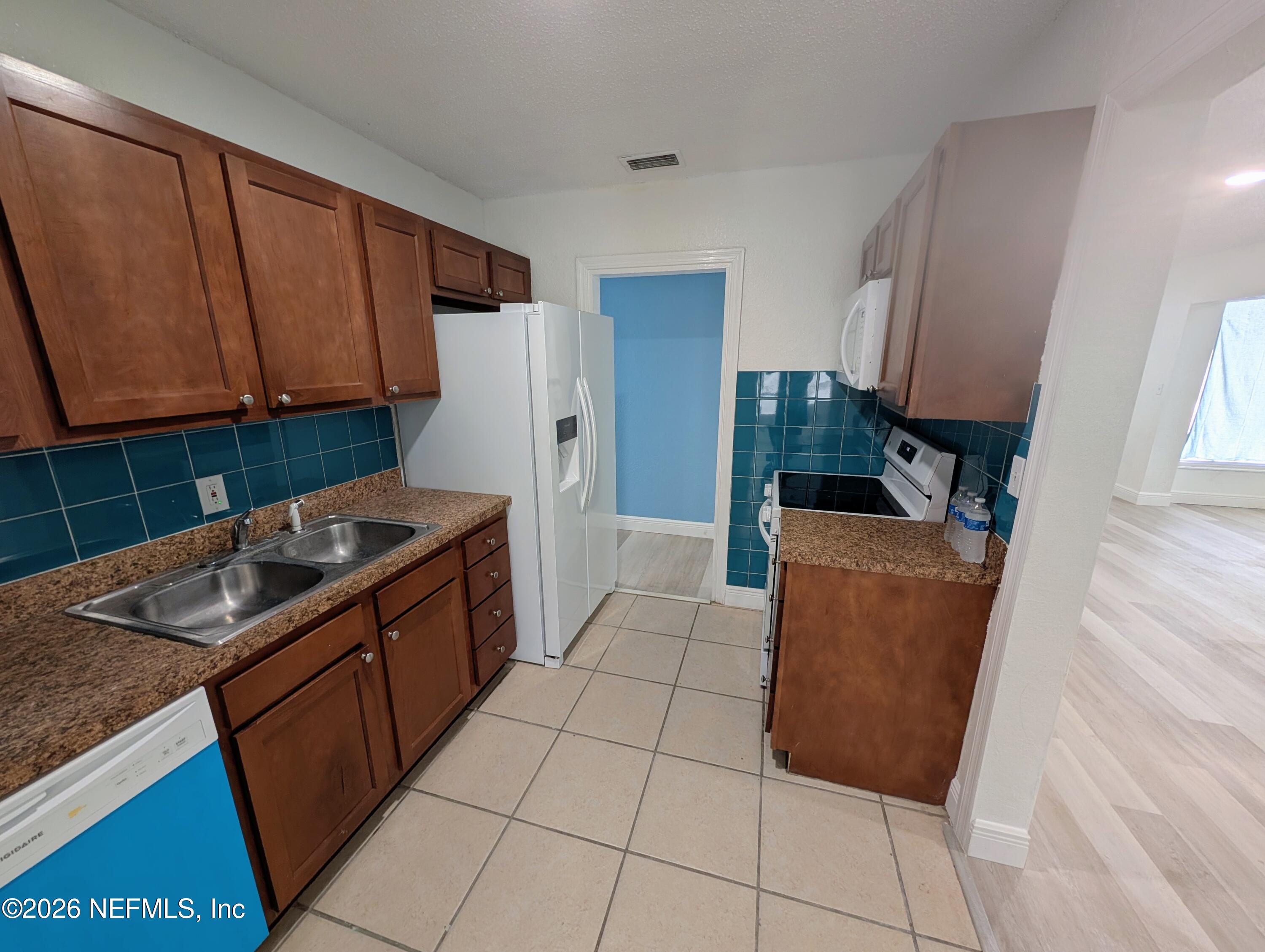 1454 Ribault Scenic Drive Jacksonville, FL 32208 - Photo 8 of 22 a kitchen with granite countertop a stove a sink a refrigerator and cabinets