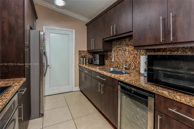 a kitchen with granite countertop a refrigerator stove and cabinets