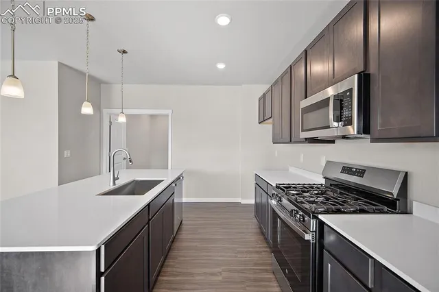 a kitchen with stainless steel appliances granite countertop a sink a stove and a wooden floors