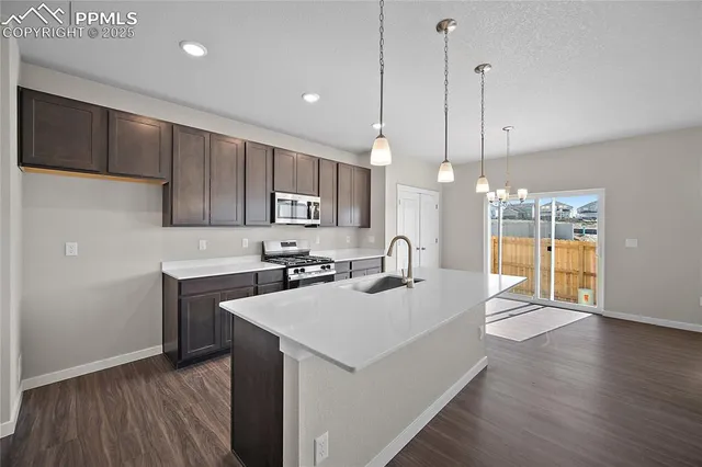 a kitchen with a sink a stove a refrigerator and island with wooden floor