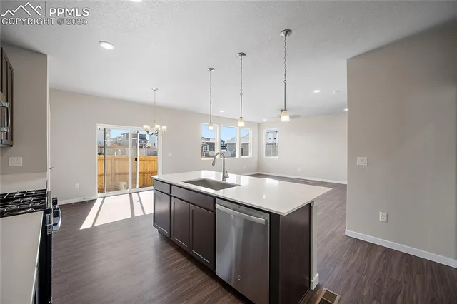 a kitchen with stainless steel appliances granite countertop a sink a stove and a wooden floor