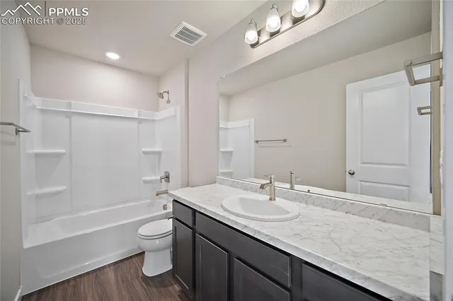 a bathroom with a granite countertop sink a toilet a shower and a mirror