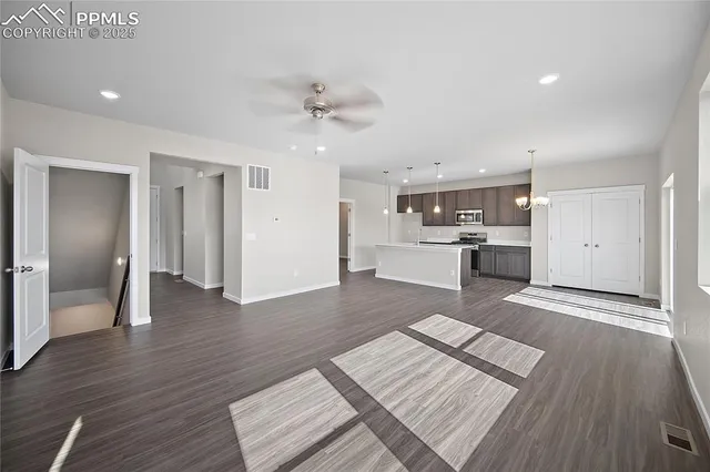 a large hall with stainless steel appliances granite countertop a refrigerator and a sink