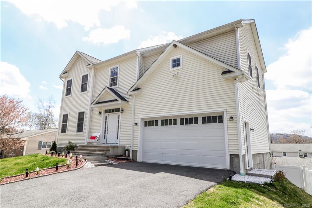 a view of a white house with a yard and table and chairs under an umbrella