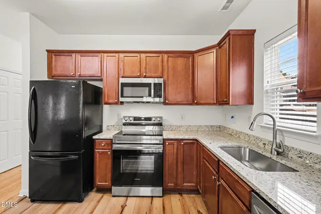 a kitchen with stainless steel appliances granite countertop a refrigerator stove and sink