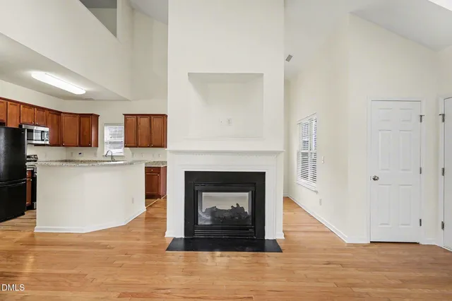 a living room with stainless steel appliances furniture a fireplace and wooden floor