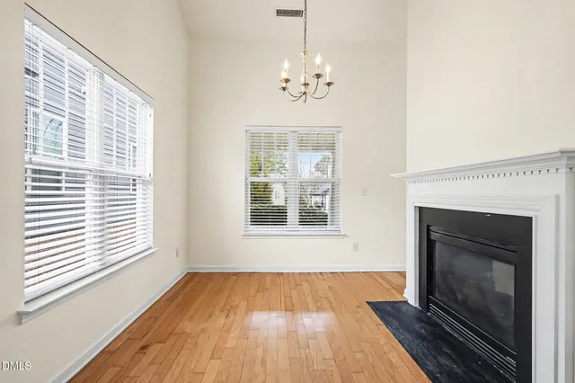 a view of an empty room with wooden floor fireplace and a window