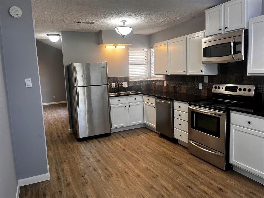 1007 Mack Place Denton, TX 76209 - Photo 7 of 37 Kitchen featuring stainless steel appliances, white cabinets, a textured ceiling, and decorative backsplash